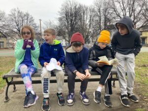 Students from Sustainability Academy on a bench at Pomeroy Park enjoying hot chocolate.